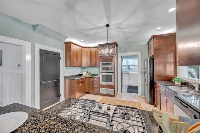 kitchen with sink, decorative light fixtures, dark stone counters, light tile patterned floors, and stainless steel appliances