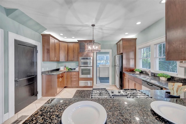 kitchen featuring appliances with stainless steel finishes, sink, hanging light fixtures, kitchen peninsula, and an inviting chandelier