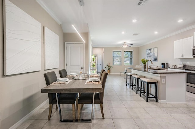 tiled dining area featuring ceiling fan, crown molding, and sink