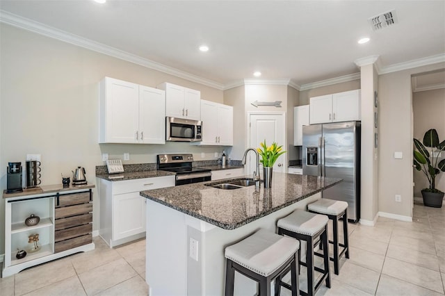 kitchen featuring sink, dark stone countertops, a kitchen island with sink, white cabinets, and appliances with stainless steel finishes