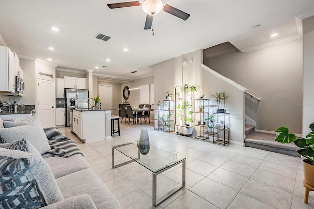 tiled living room with crown molding, sink, and ceiling fan