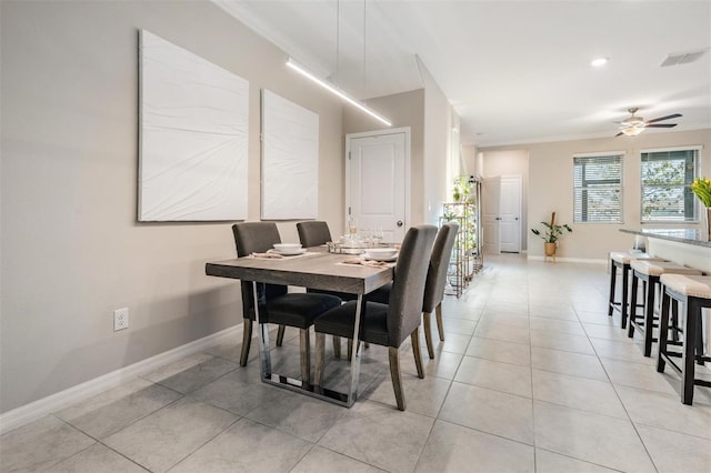 tiled dining space with ceiling fan and crown molding