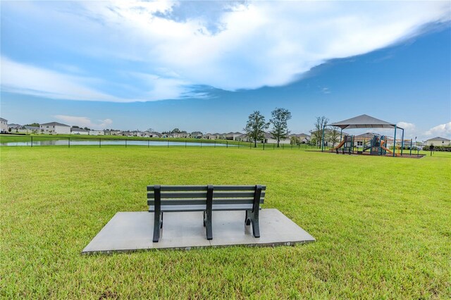 view of home's community with a yard, a playground, and a water view