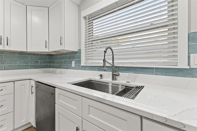 kitchen with white cabinets, dishwasher, light stone counters, and sink