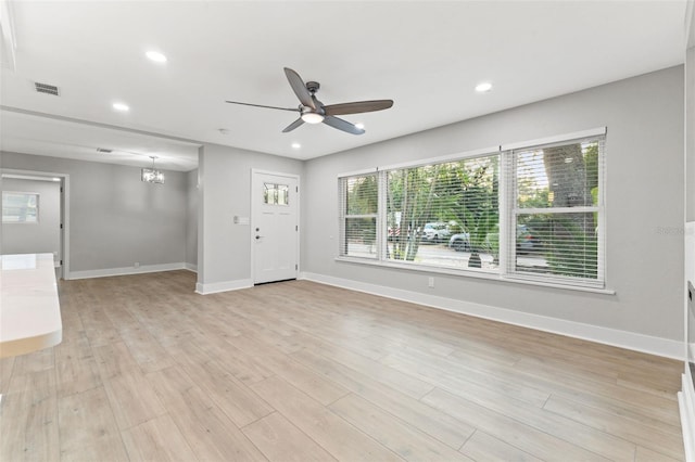 interior space featuring a healthy amount of sunlight, ceiling fan with notable chandelier, and light wood-type flooring