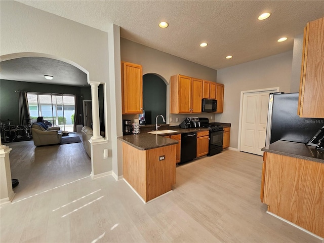 kitchen with black appliances, sink, light wood-type flooring, a textured ceiling, and ornate columns