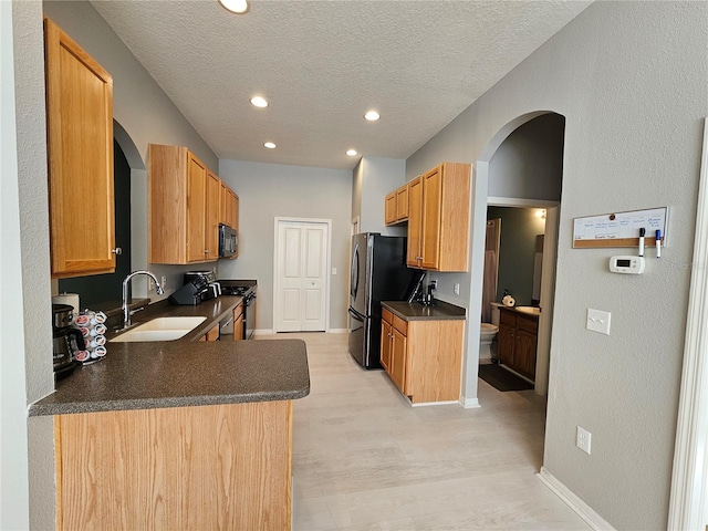 kitchen featuring appliances with stainless steel finishes, light wood-type flooring, a textured ceiling, and sink