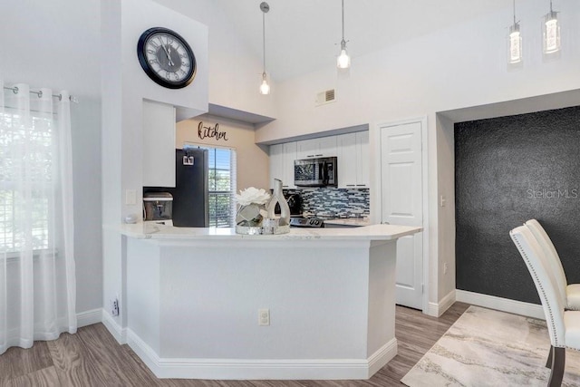 kitchen with kitchen peninsula, white cabinets, hanging light fixtures, and hardwood / wood-style flooring