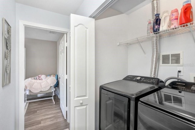 laundry area with washing machine and dryer and wood-type flooring