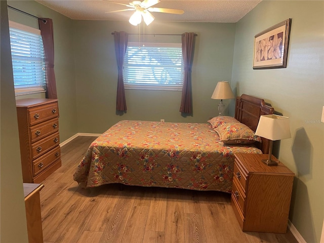 bedroom with a textured ceiling, light hardwood / wood-style flooring, multiple windows, and ceiling fan