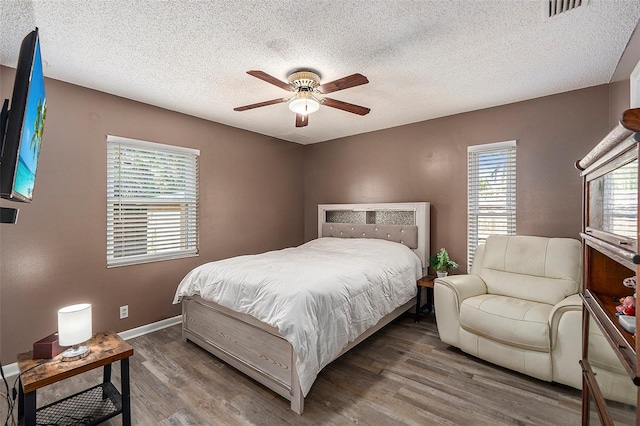 bedroom with hardwood / wood-style floors, a textured ceiling, and ceiling fan