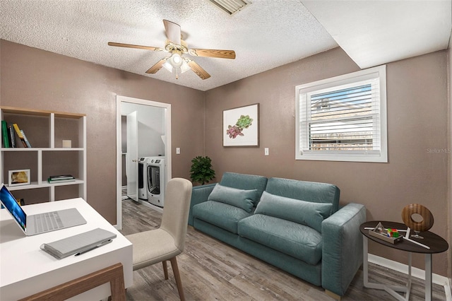 home office with a textured ceiling, hardwood / wood-style flooring, washer and clothes dryer, and ceiling fan