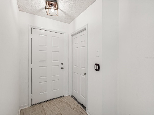 doorway to outside featuring a textured ceiling