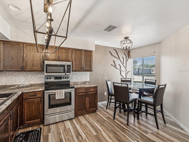 kitchen featuring tasteful backsplash, light hardwood / wood-style flooring, appliances with stainless steel finishes, and a chandelier