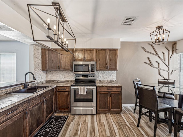 kitchen featuring sink, stainless steel appliances, tasteful backsplash, light hardwood / wood-style flooring, and decorative light fixtures