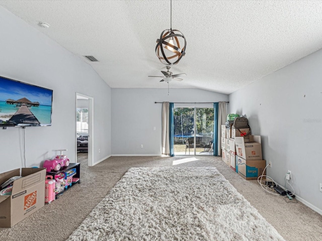 interior space featuring a textured ceiling, carpet floors, vaulted ceiling, and ceiling fan