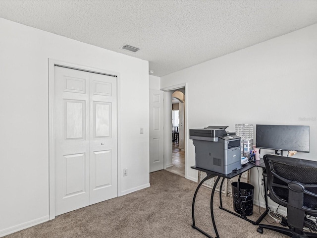 office area featuring a textured ceiling and light carpet