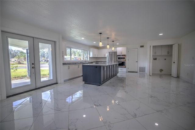 kitchen featuring pendant lighting, stainless steel appliances, a kitchen island, and french doors