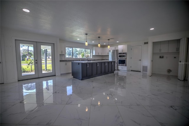 kitchen with decorative light fixtures, a kitchen island, white cabinetry, and a wealth of natural light