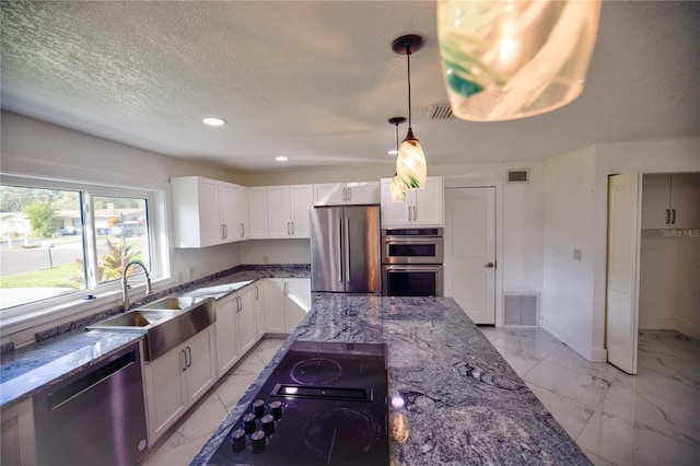 kitchen featuring appliances with stainless steel finishes, sink, stone counters, white cabinetry, and hanging light fixtures