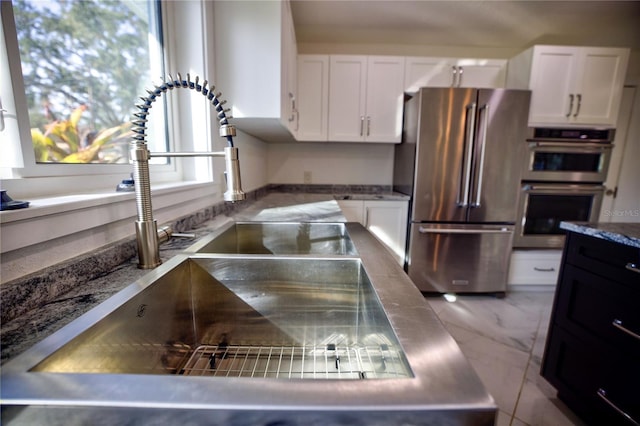 1042 Idlewild Dr N, Dunedin, FL 34698 - kitchen featuring appliances with stainless steel finishes, white cabinetry, a sink, light stone countertops, and marble finish flooring