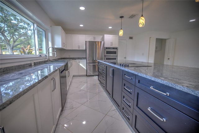 kitchen featuring light stone countertops, appliances with stainless steel finishes, sink, decorative light fixtures, and white cabinets