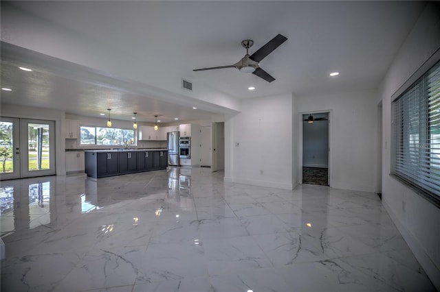 unfurnished living room featuring french doors, ceiling fan, and sink