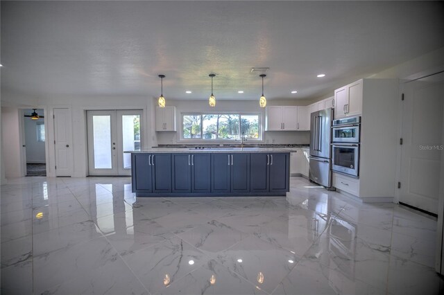 kitchen featuring a center island, blue cabinets, hanging light fixtures, appliances with stainless steel finishes, and white cabinetry