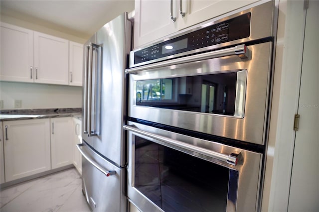 kitchen with light stone counters, white cabinetry, and high quality fridge