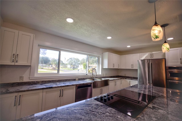 kitchen featuring dark stone countertops, hanging light fixtures, white cabinets, and stainless steel appliances