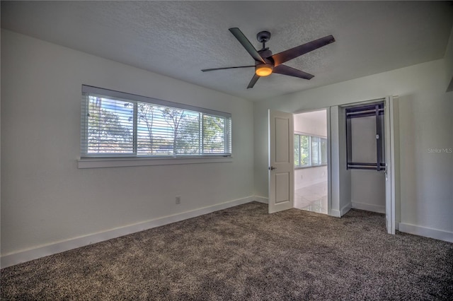 unfurnished bedroom with a textured ceiling, carpet floors, a closet, and ceiling fan