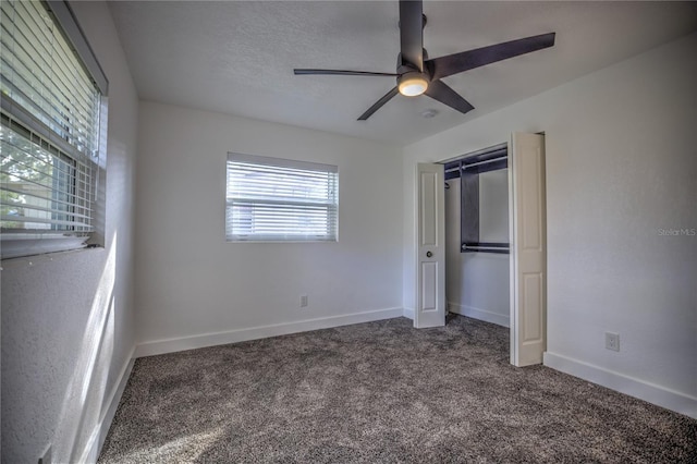 unfurnished bedroom with dark colored carpet, ceiling fan, a textured ceiling, and a closet