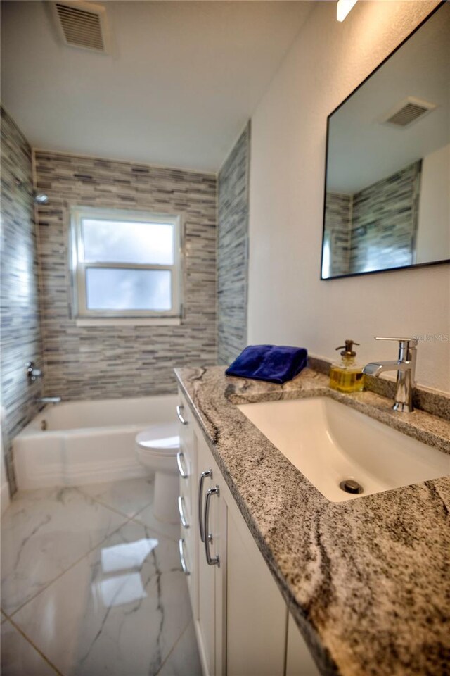 full bathroom with vanity, tiled shower / bath combo, and toilet