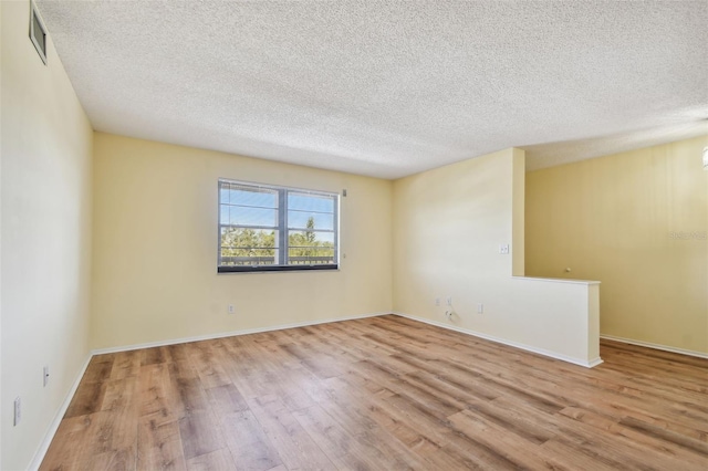 spare room featuring a textured ceiling and light hardwood / wood-style flooring