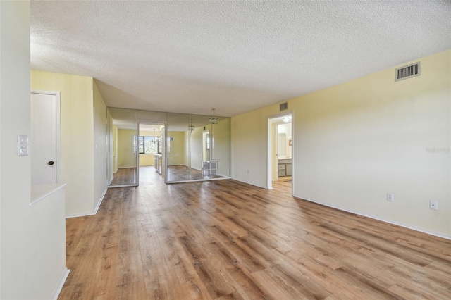 interior space with a textured ceiling and light hardwood / wood-style flooring