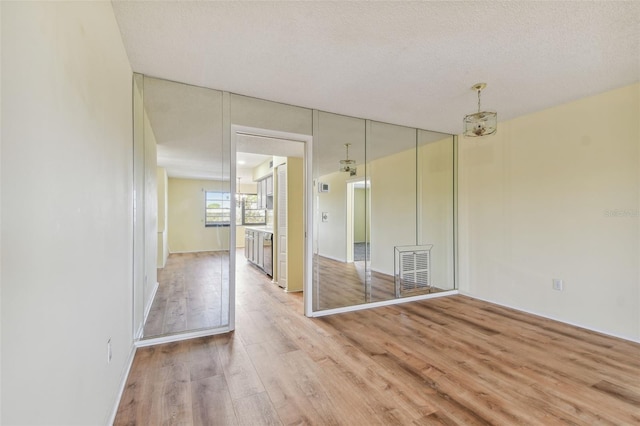 unfurnished room featuring light hardwood / wood-style flooring and a textured ceiling