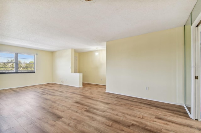 empty room with light hardwood / wood-style flooring and a textured ceiling