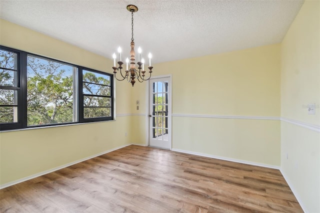 unfurnished room with a textured ceiling, hardwood / wood-style flooring, and a notable chandelier