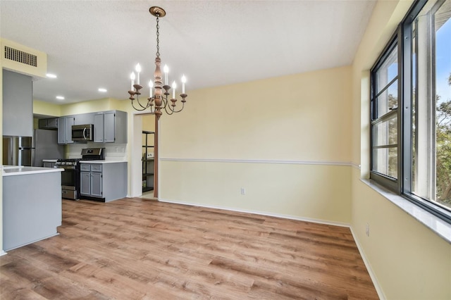8198 Terrace Garden Dr N Unit 403, Saint Petersburg, FL 33709 - kitchen with appliances with stainless steel finishes, a chandelier, gray cabinetry, baseboards, and light wood-style flooring