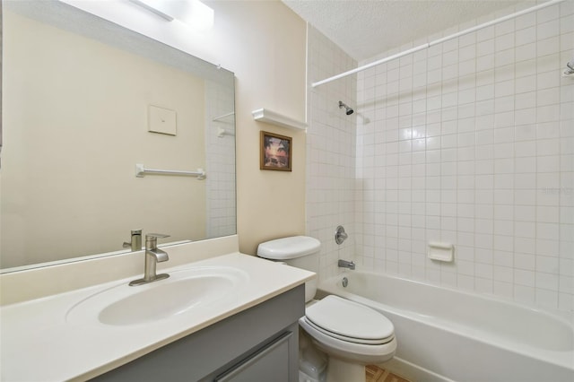 full bathroom featuring vanity, toilet, a textured ceiling, and tiled shower / bath combo