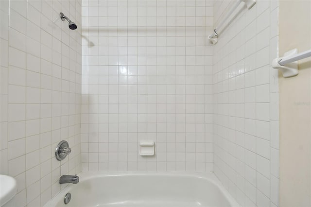 bathroom with toilet and tiled shower / bath