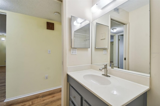 8198 Terrace Garden Dr N Unit 403, Saint Petersburg, FL 33709 - bathroom with a textured ceiling, wood finished floors, vanity, and baseboards