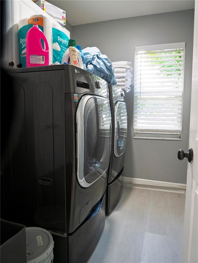 laundry area with washing machine and clothes dryer and hardwood / wood-style floors