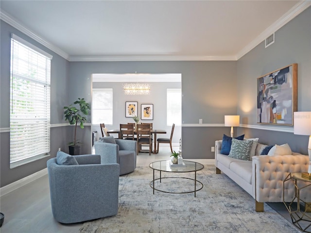 living room with hardwood / wood-style flooring, an inviting chandelier, and crown molding