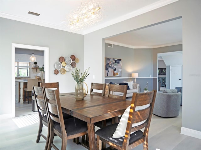 dining space featuring light hardwood / wood-style floors, ornamental molding, and an inviting chandelier