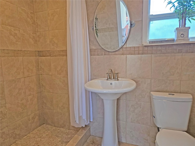 bathroom featuring toilet, curtained shower, and tile walls