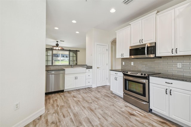 kitchen with sink, white cabinets, light wood-type flooring, and appliances with stainless steel finishes