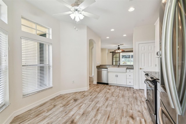 kitchen with white cabinets, sink, ceiling fan, appliances with stainless steel finishes, and light hardwood / wood-style floors