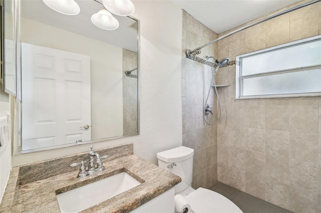 bathroom with vanity, toilet, and tiled shower