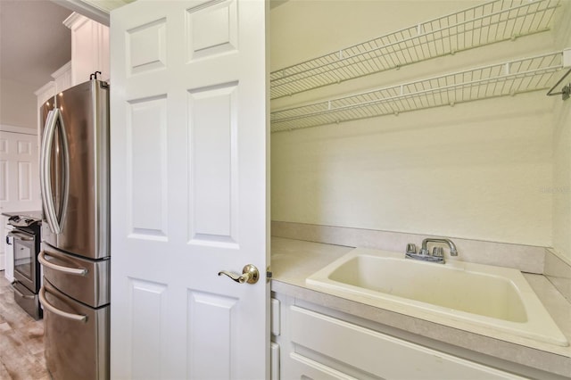 clothes washing area featuring sink and light hardwood / wood-style flooring